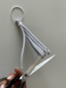 DIY-Idee: Quasten für Lenker des Velos, Schritt 3: Schnur / Band durchziehen und Enden mit Schere durchschneiden